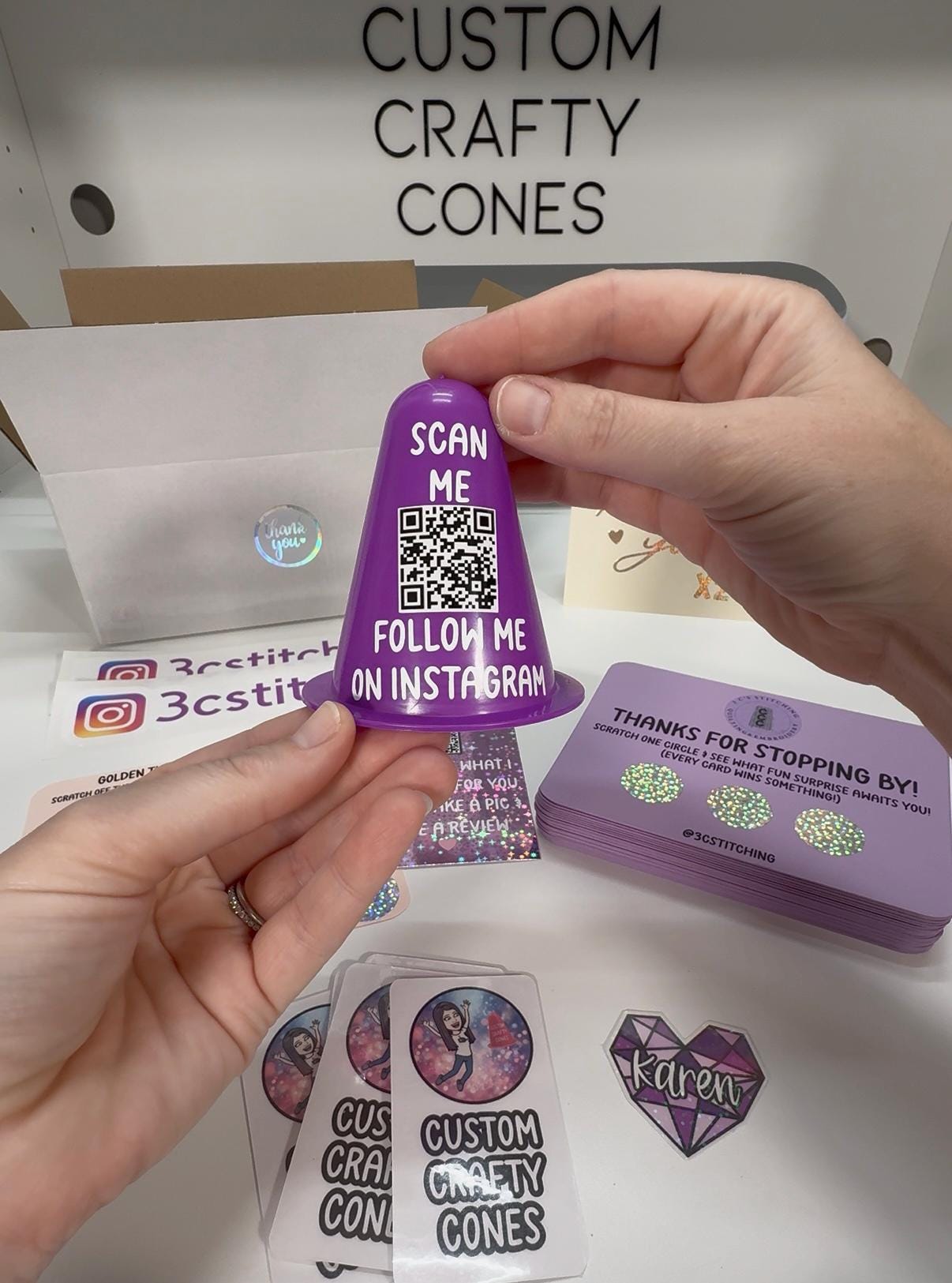 Laura holding a finished custom QR-code cone above her worktable